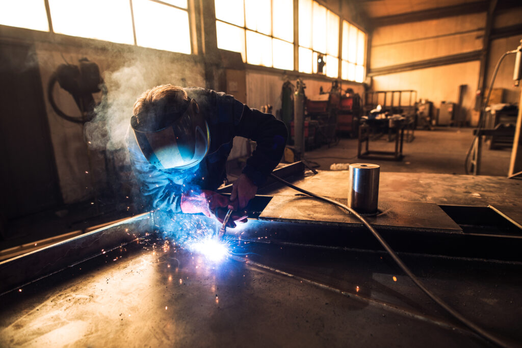 professional-welder-protective-uniform-helmet-welding-metal-part-workshop-1024x683 TIG-Schweißen in der Industrie: Wo es sich am besten bewährt und warum?